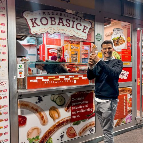 kobasice-belgrade-serbian-hot-dog Αγόρι κρατάει Σερβικό hot dog μπροστά από το μαγαζί που μόλις το αγόρασε