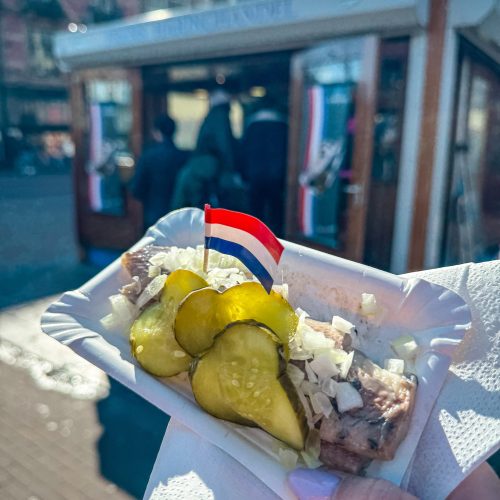 herring-amsterdam-traditional-food κομματιασμένη ρέγγα σε χάρτινο πιατάκι, με κρεμμύδι και πίκλα