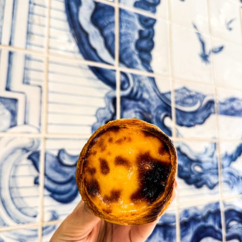 pastel-de-nata το διάσημο ποροτγαλικό γλυκό pastel de nata μπροστά σε γαλάζια πλακάκια στη Λισαβόνα