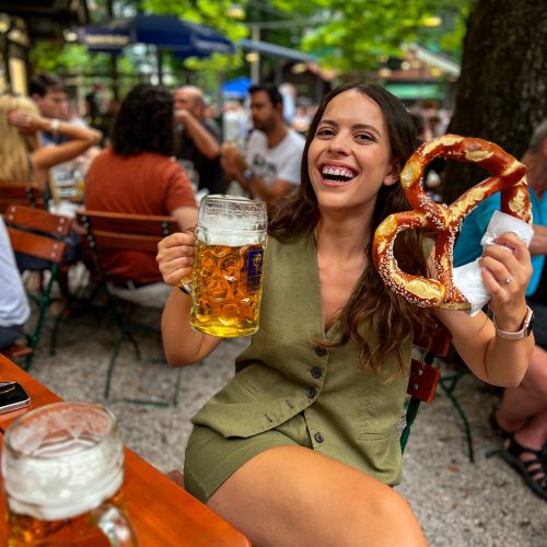 augustiner-anna-trakada κορίτσι κρατάει μπίρα ενός λίτρου και ένα γιγάντιο πρέτσελ στο άλλο χέρι