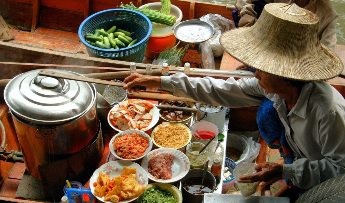 γυναίκα μαγειρεύει street food στην Ταϊλάνδη πάνω σε βάρκα