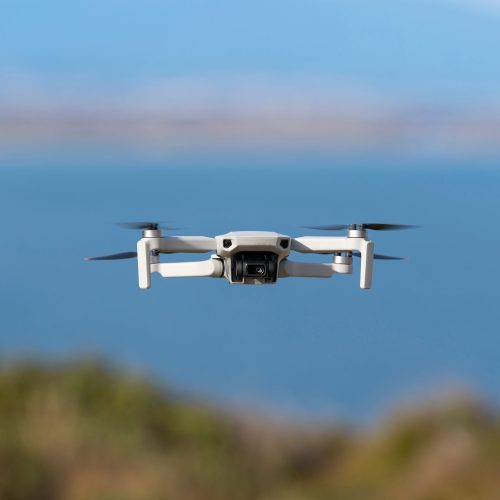 Small,Drone,Flying,Still,With,A,Defocused,Sea,Background Small drone flying still with a defocused sea background